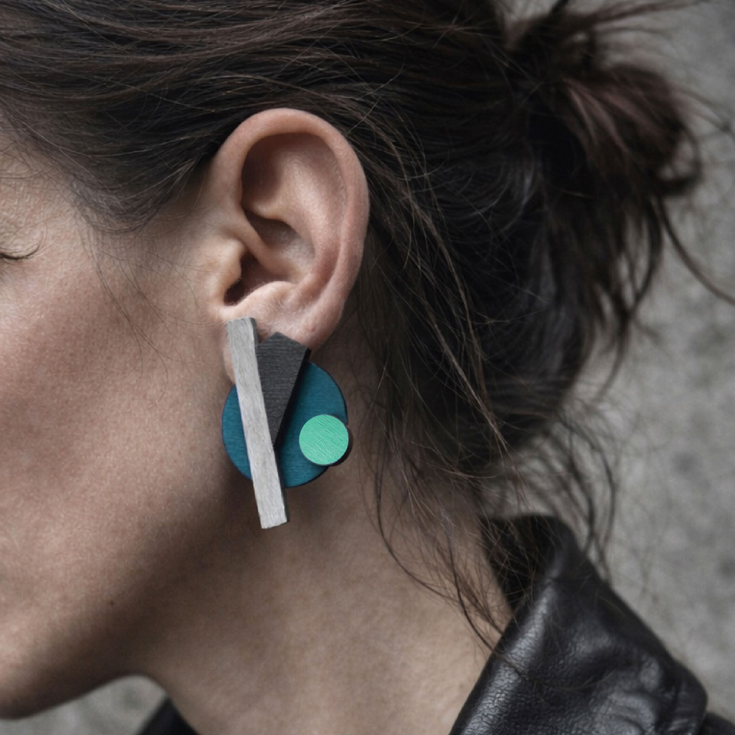 Large wooden lightweight earrings on ear with modern geometric shapes in petrol, black and mint